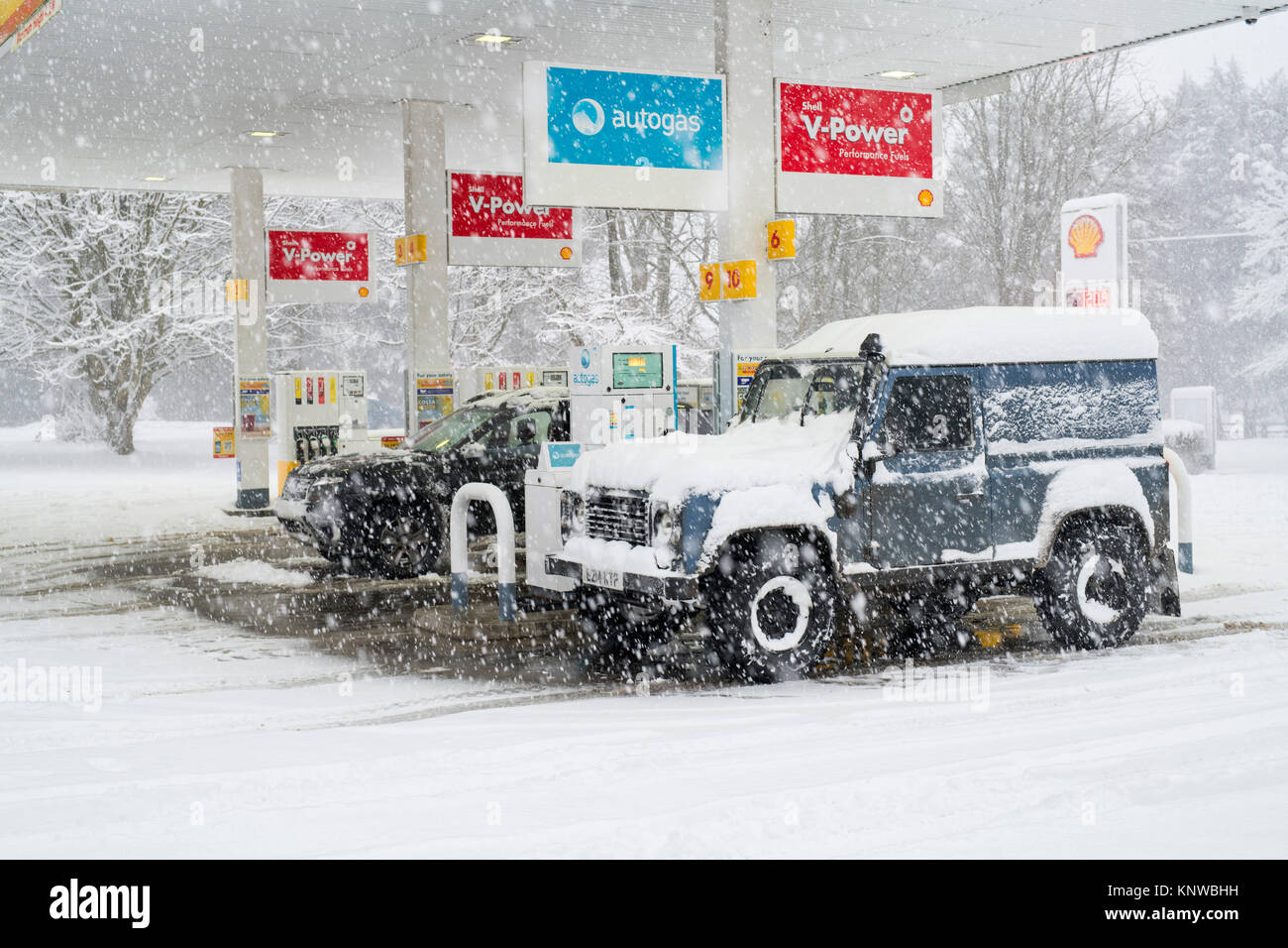 Land Rover und Dacia Duster in einer Tankstelle im Schnee. Chipping Norton, Oxfordshire, England Stockfoto