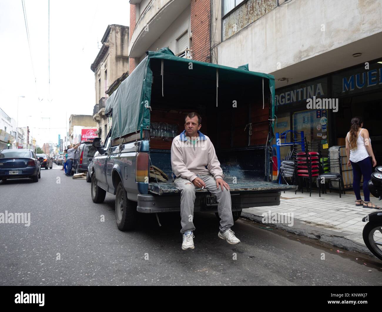 Cordoba, Argentinien - 2016: ein Mann nimmt einen Bruch und die Sitze beim Rauchen einer Zigarette nach dem Entladen Möbel in ein Geschäft von einem Pickup Truck. Stockfoto