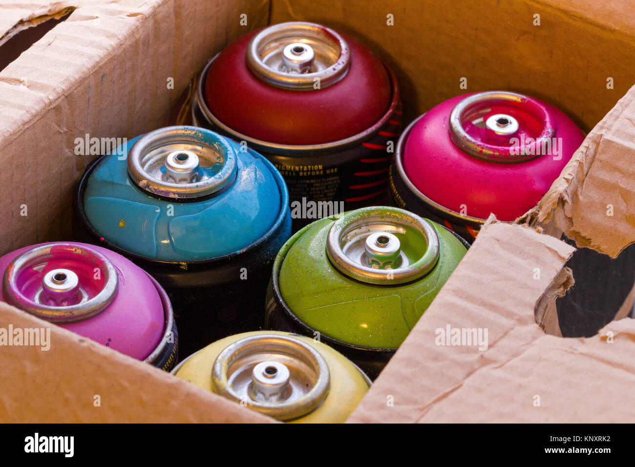 Kiste voll mit bunten Spraydosen. Stockfoto