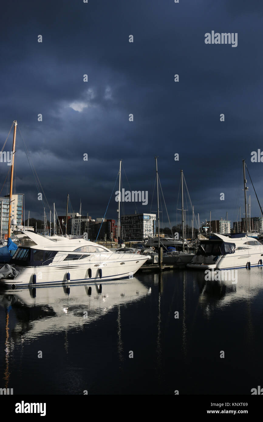 Ipswich Waterfront Marina und die umliegenden Gebäude mit sehr dunklen Sturmwolken und Sonnenlicht, die die Boote und Gebäude erleuchten Stockfoto