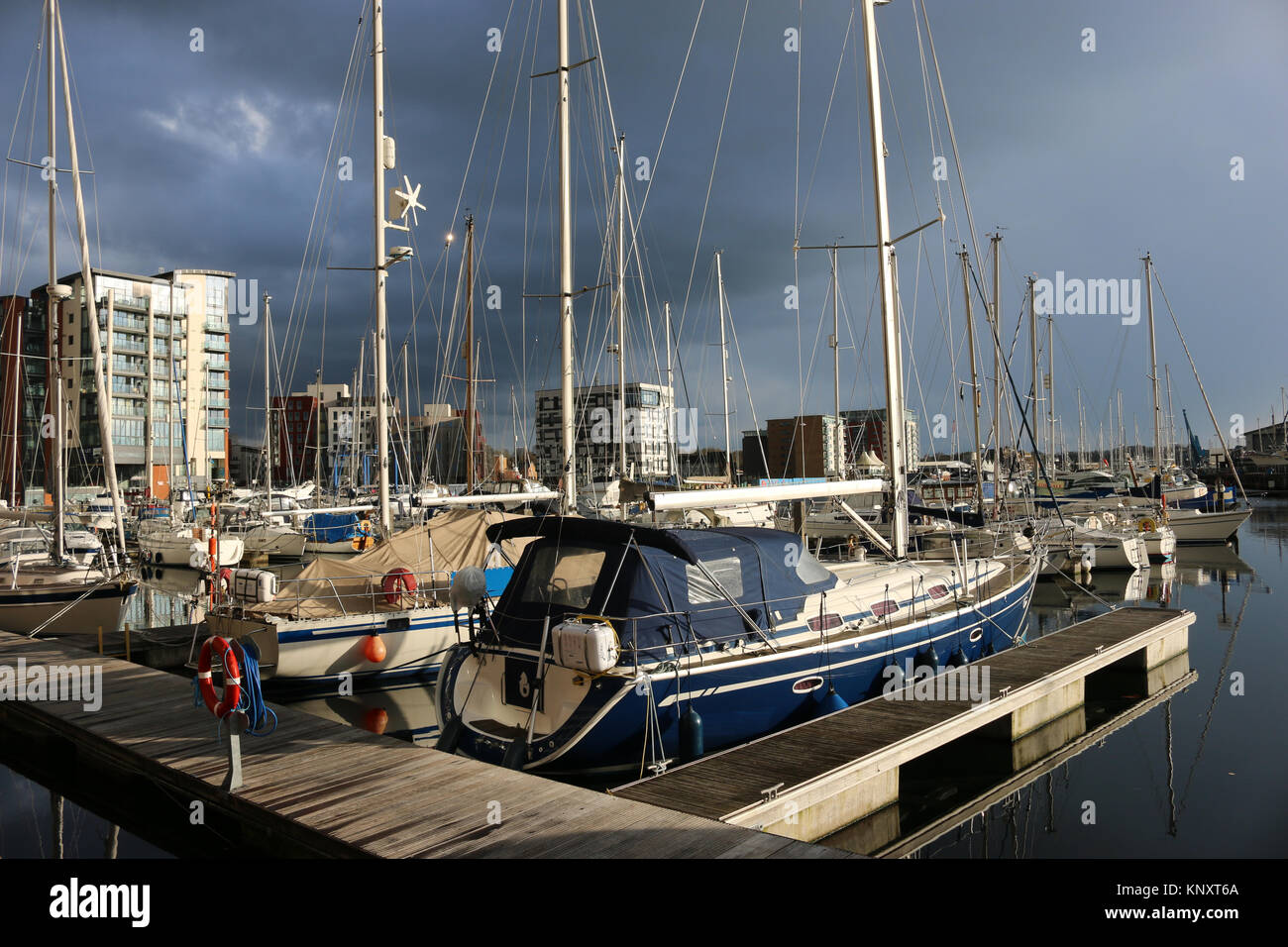 Ipswich Waterfront Marina und die umliegenden Gebäude mit sehr dunklen Sturmwolken und Sonnenlicht, die die Boote und Gebäude erleuchten Stockfoto