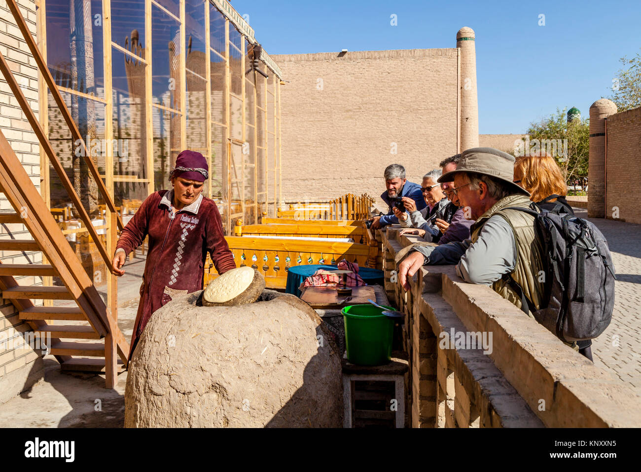 Eine lokale Frau backt Brot in einem traditionellen Lehmofen beobachtete eine Gruppe von Touristen, Chiwa, Usbekistan Stockfoto