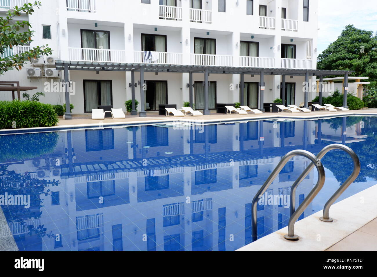 Hotel, Stühlen und einem blauen Pool Stockfoto