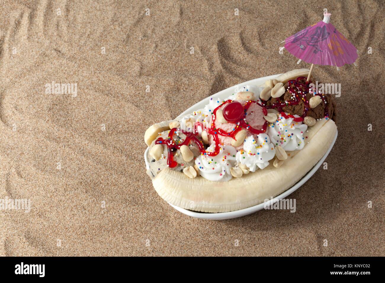 Eine Schüssel mit Banana Split eisbecher am Strand sand Stockfoto