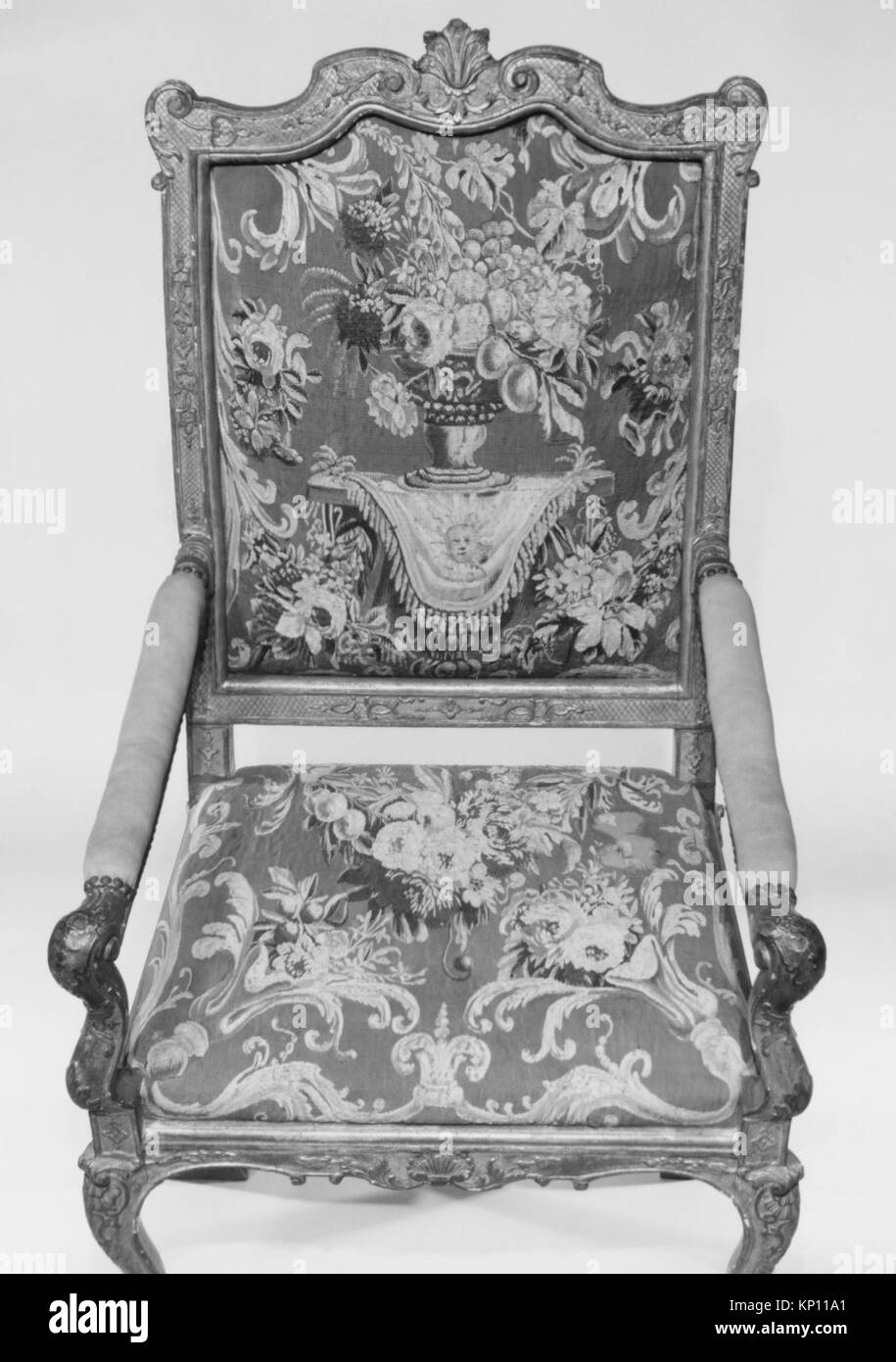 Ein französischer Sessel (Fauteuil) aus dem ersten Viertel des 18. Jahrhunderts, geschnitztes und vergoldetes Buchenholz mit Wandteppichen aus Wolle Aubusson, 47 1/2 x 27 1/2 x 21 5/8 cm, Teil der MET-Kollektion, die das französische Möbeldesign und die dekorative Kunst der Zeit veranschaulicht. Stockfoto