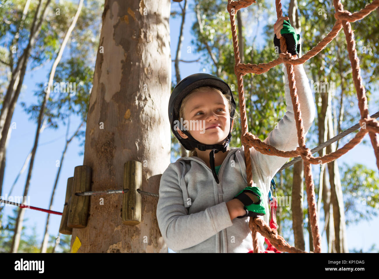 Kleines Mädchen tragen Helm fertig, am Seil Zaun in den Wald zu klettern Stockfoto