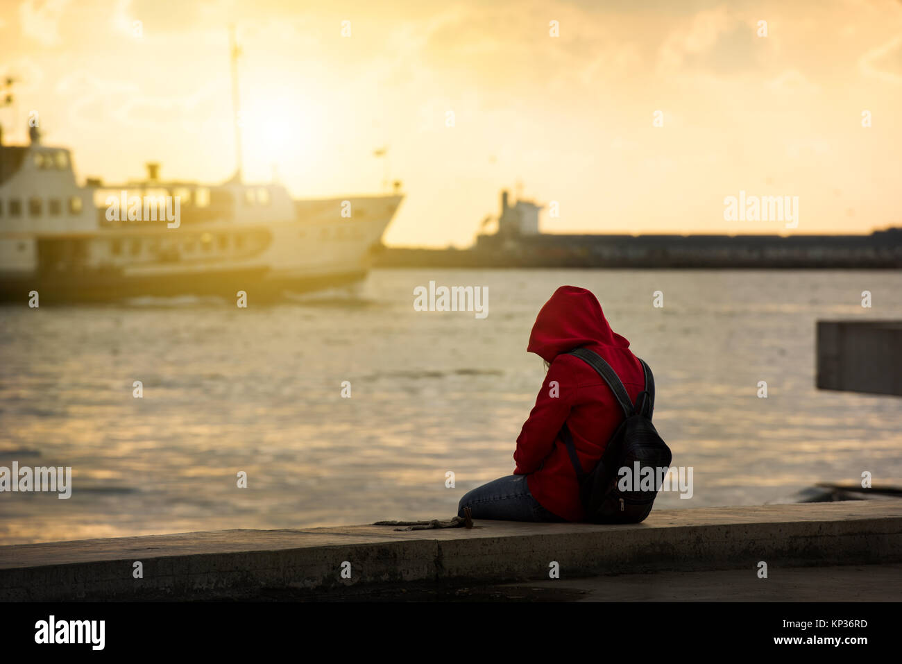 Einsame Mädchen sitzt am Hafen Stockfoto