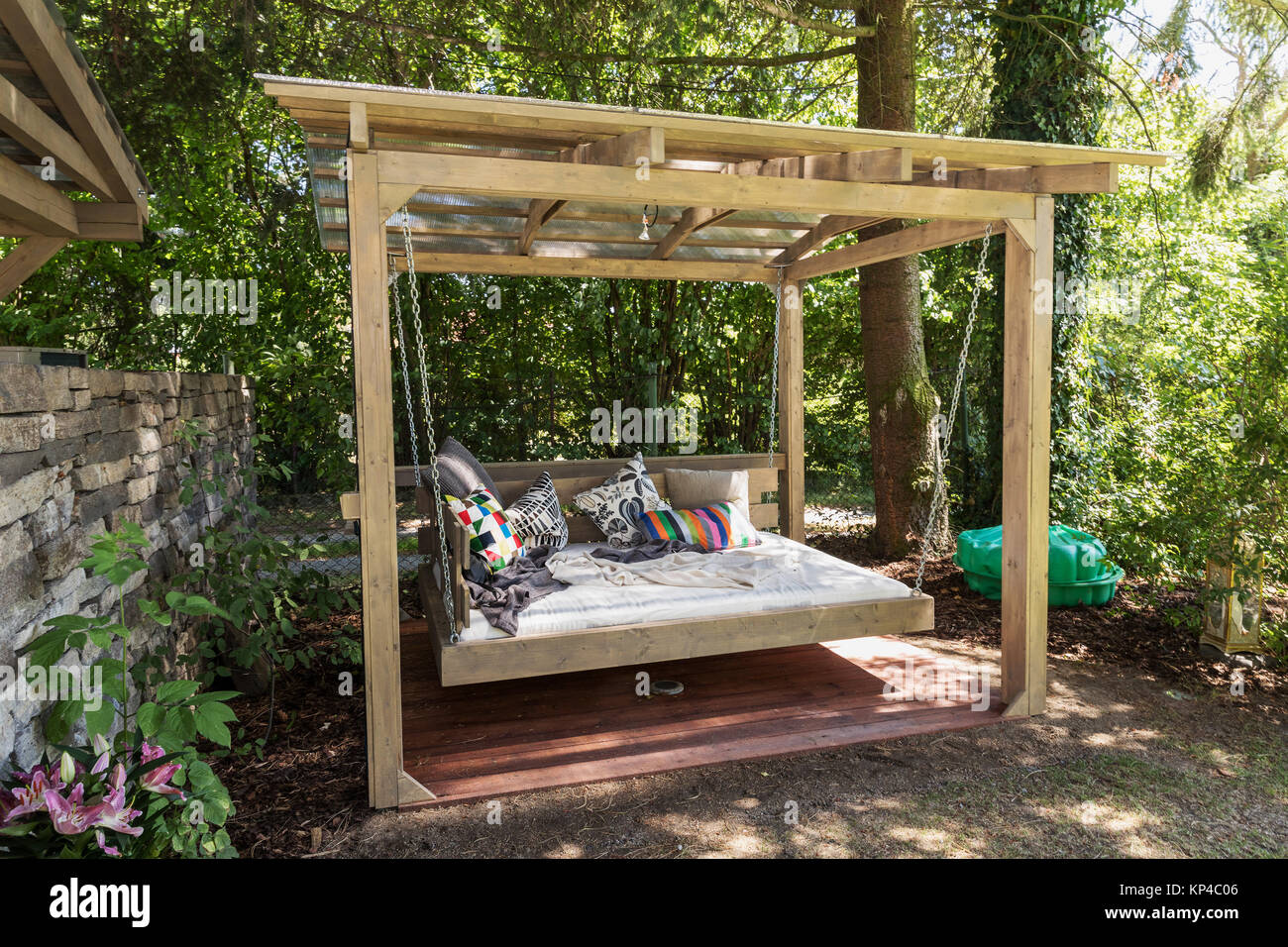 Große Schaukel im Bett. Chaiselongue im Garten, Pergola. Garten Bett mit Kissen. Großen Bett zum Sonnenbaden und Ausruhen. Vier Garden Bed. Stockfoto