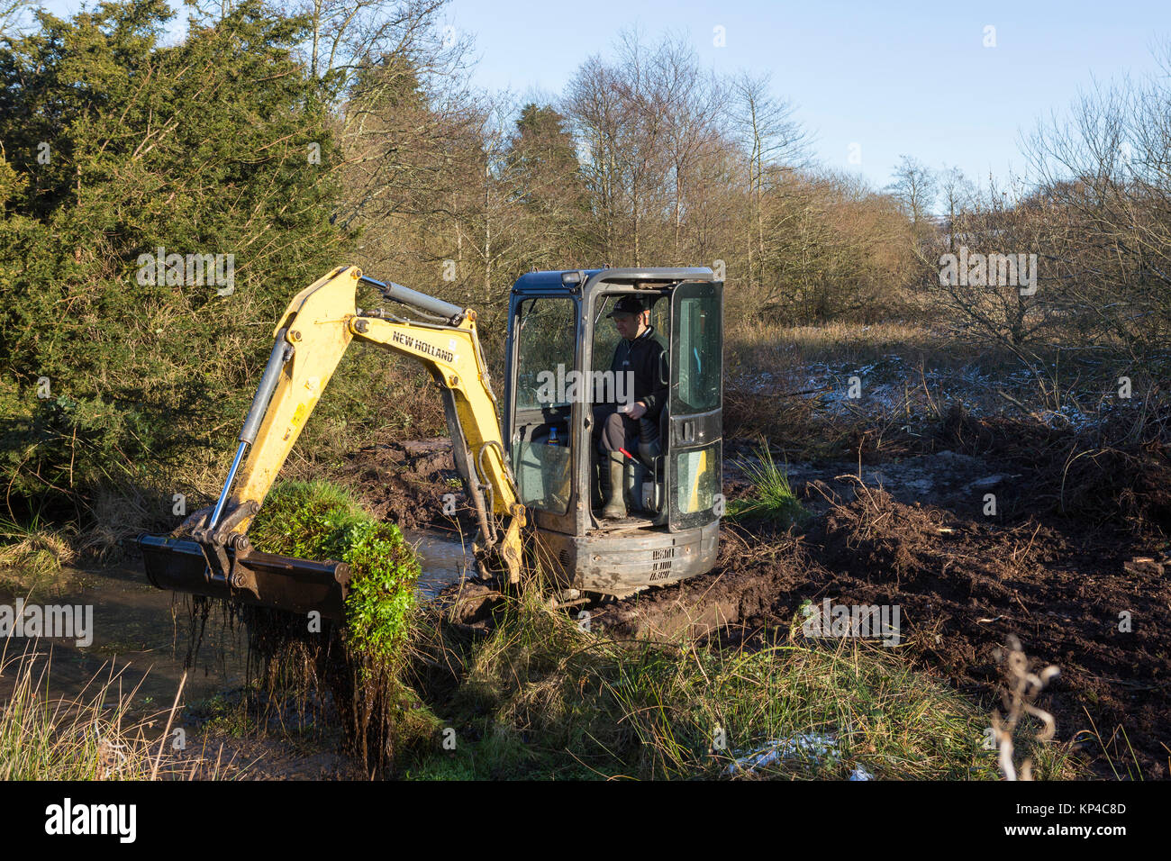 Ein Bagger gräbt ein Teich in der Landschaft Stockfoto