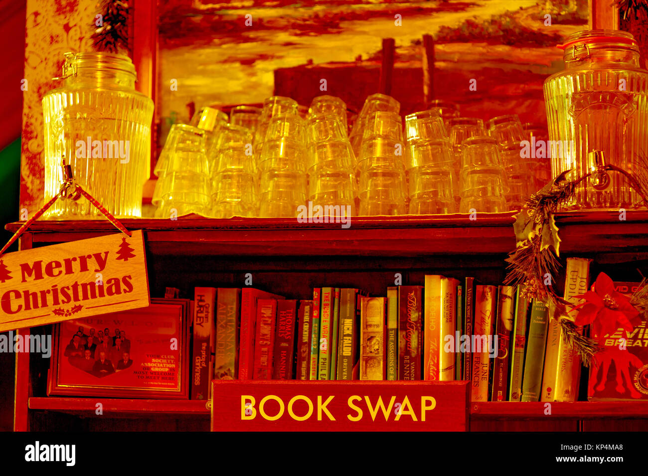 Bücherregal mit Trinkgläser und Bücher mit Weihnachtsschmuck In einem getönten Bild Stockfoto