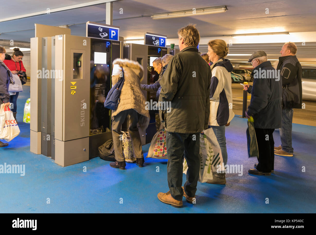 Warteschlange von Menschen in einem Parkhaus in Großbritannien warten ein Ticket von Parkscheinautomaten zu kaufen. Stockfoto