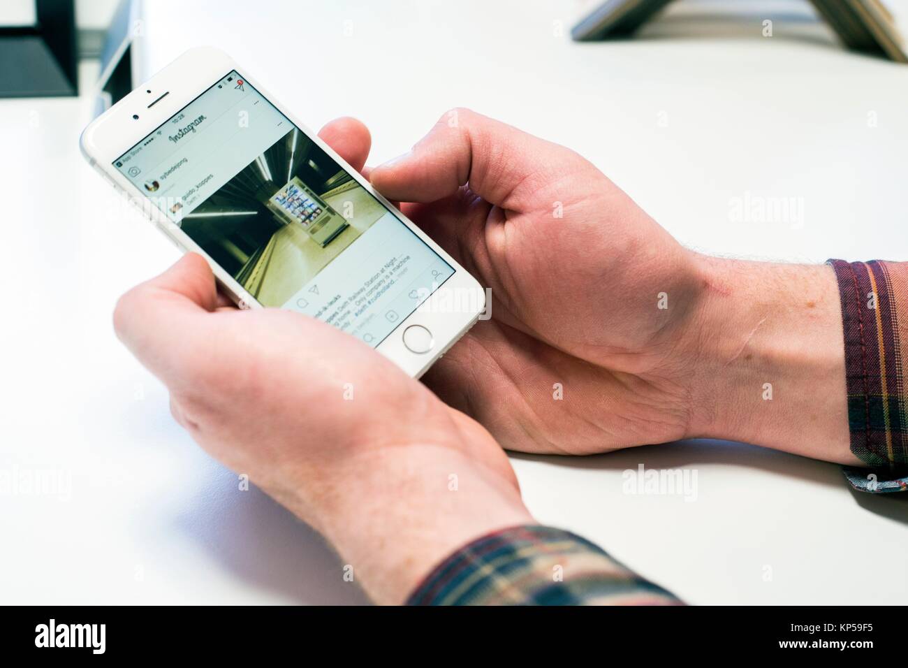 Goirle, Niederlande. Mitte der erwachsenen männlichen Handwerker und Bild Framemaker, Anzeigen von Aufnahmen auf dem Instagram App von seinem Smartphone. Stockfoto