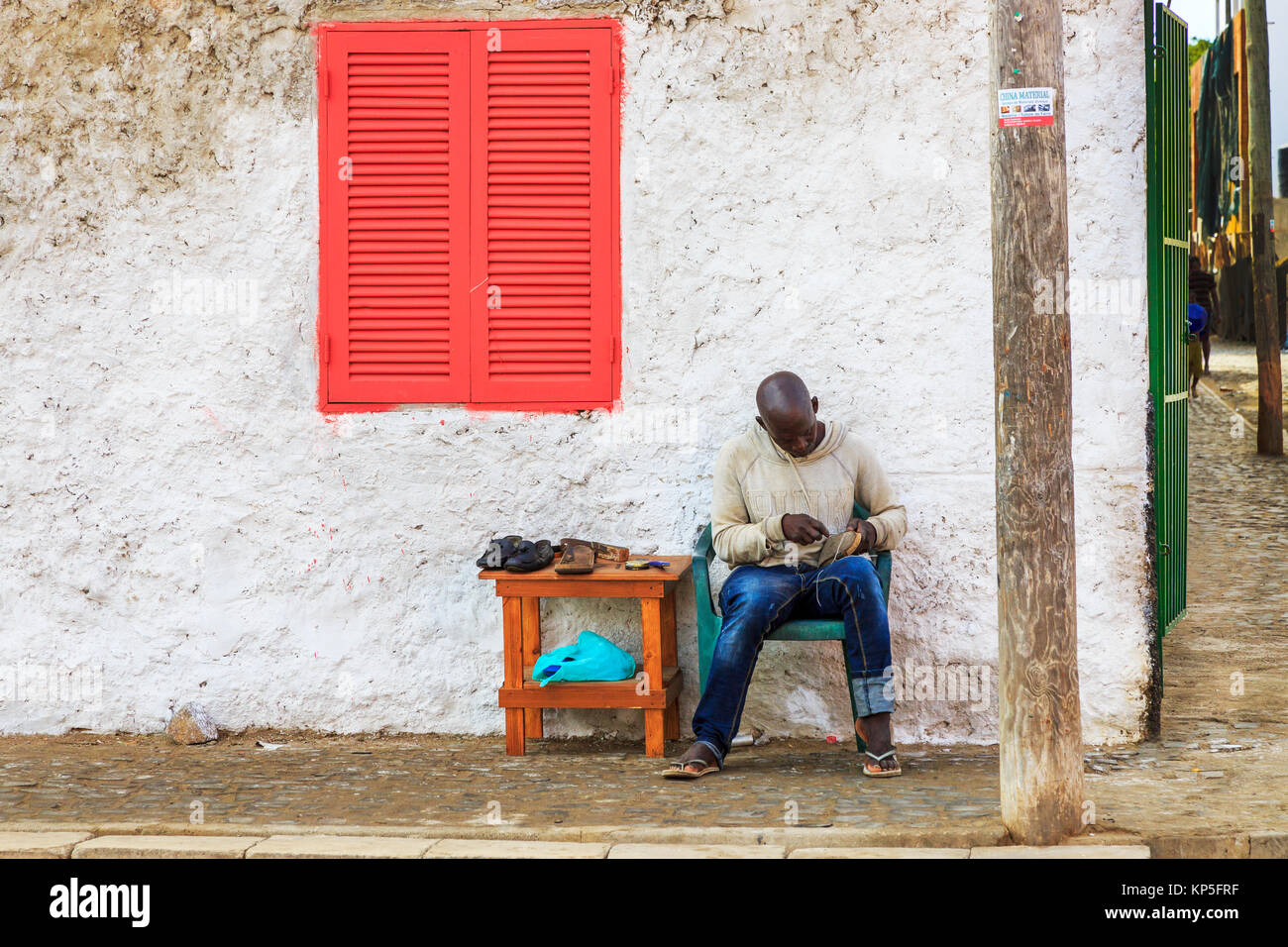 Lokaler Mann arbeitet als Schuster in den Gassen von Santa Maria, Insel Sal, Sal, Kap Verde, Afrika Stockfoto