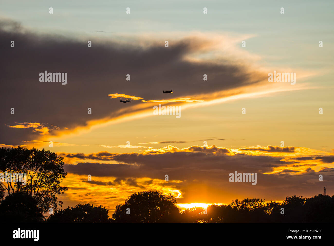 Sunset Air Show beim Goodwood Revival 2017. Spitfire und P-51 Mustang 2. Weltkrieg Kampfflugzeuge fliegen in der Abenddämmerung Stockfoto