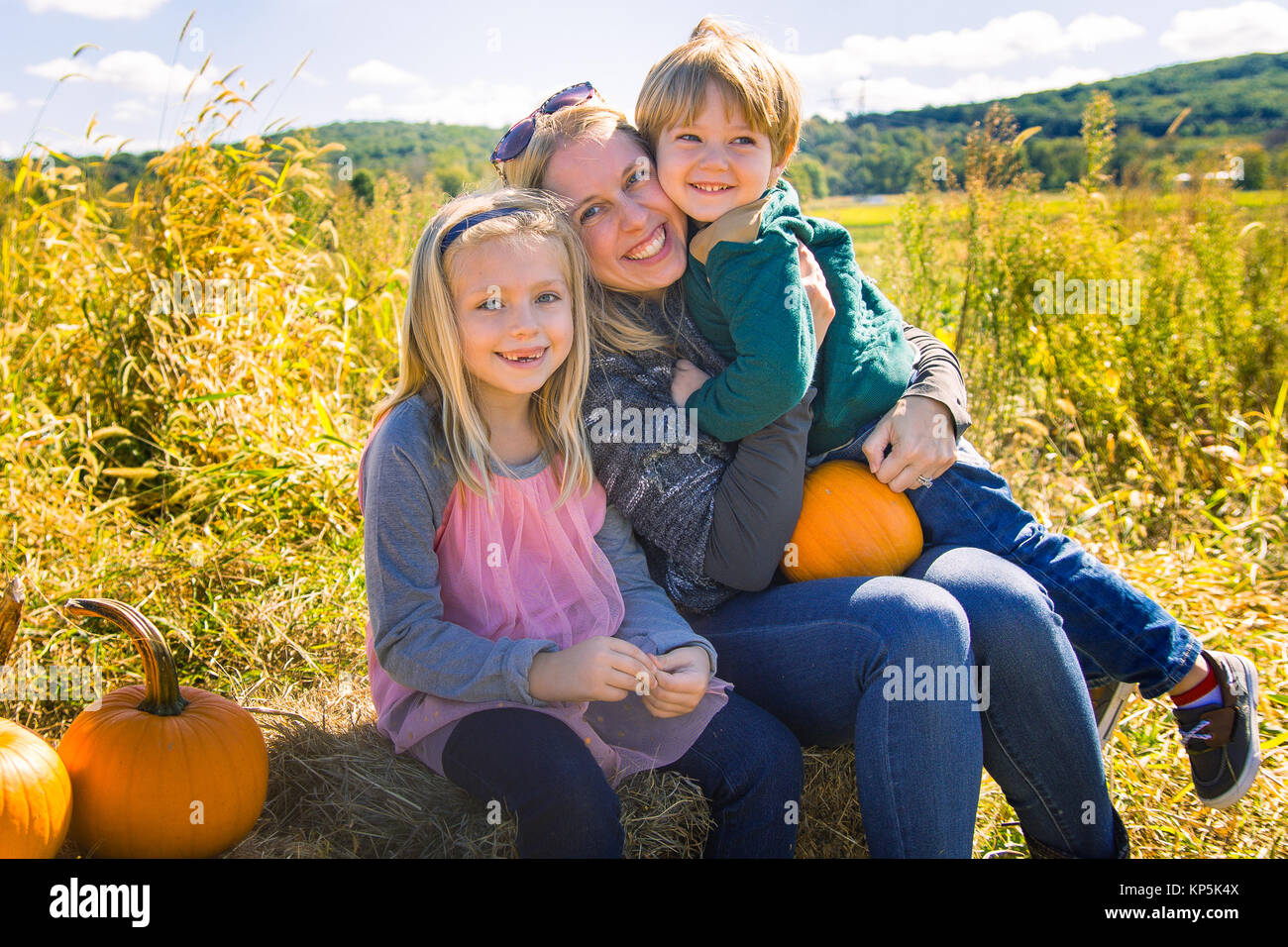 Mutter mit Sohn und Tochter sitzen mit Kürbisse auf dem Bauernhof Stockfoto