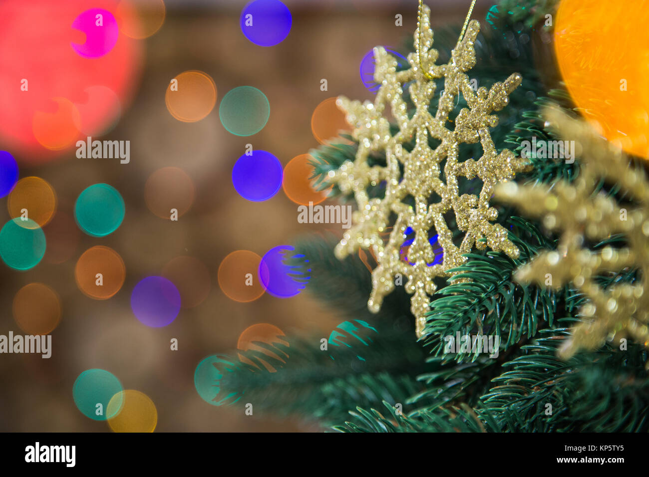 Detailansicht der wunderschöne Goldene runde Schneeflocken hängend an grünen Weihnachtsbaum Niederlassungen in Home Interior. Dekorierte Tanne an verschwommen Lichter von Co Stockfoto