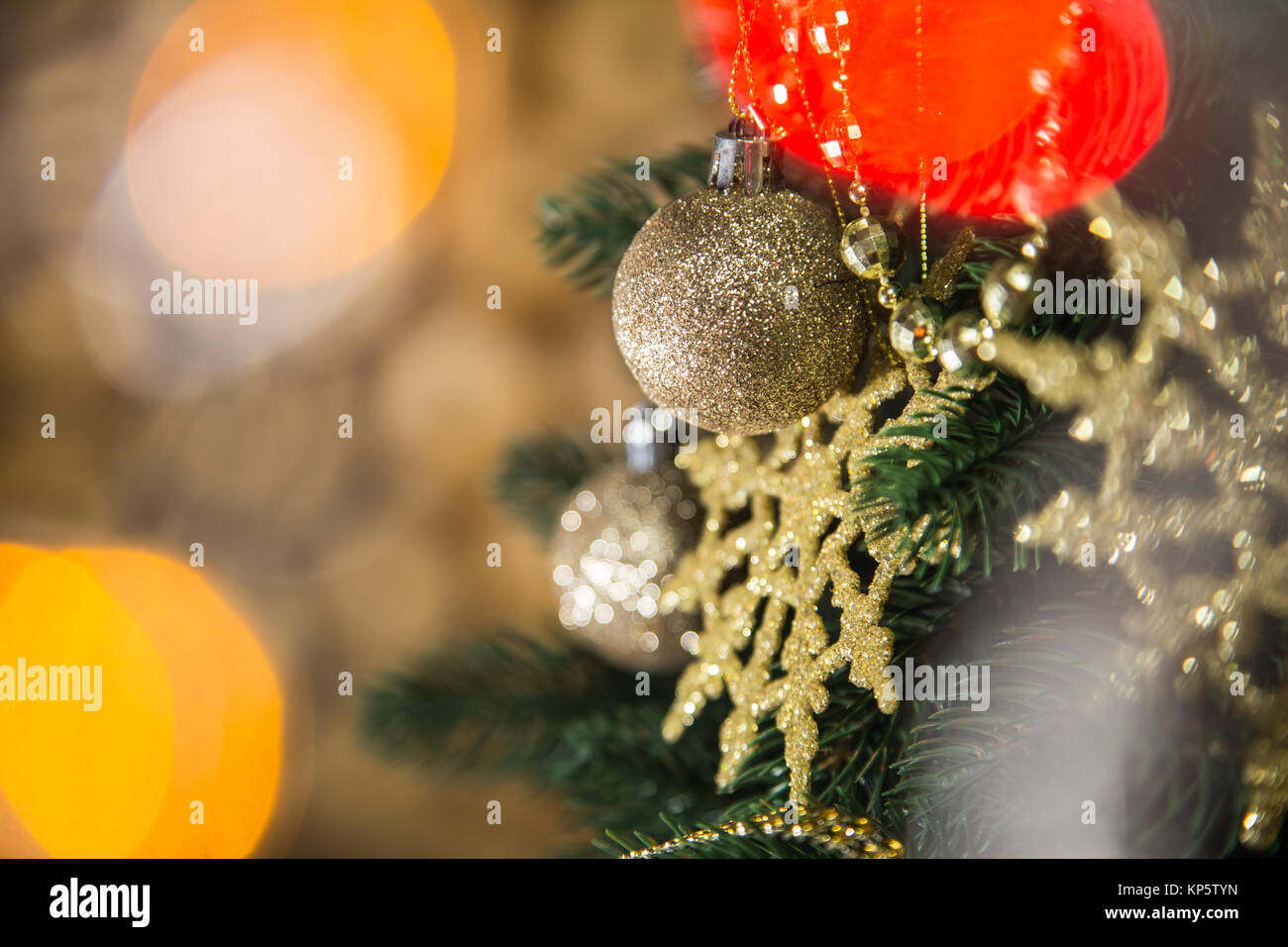 Detailansicht der Schönen glänzenden goldenen runde Schneeflocken und Kugeln am Weihnachtsbaum Niederlassungen in Home Interior hängen. Dekorierte Tanne an blurry li Stockfoto