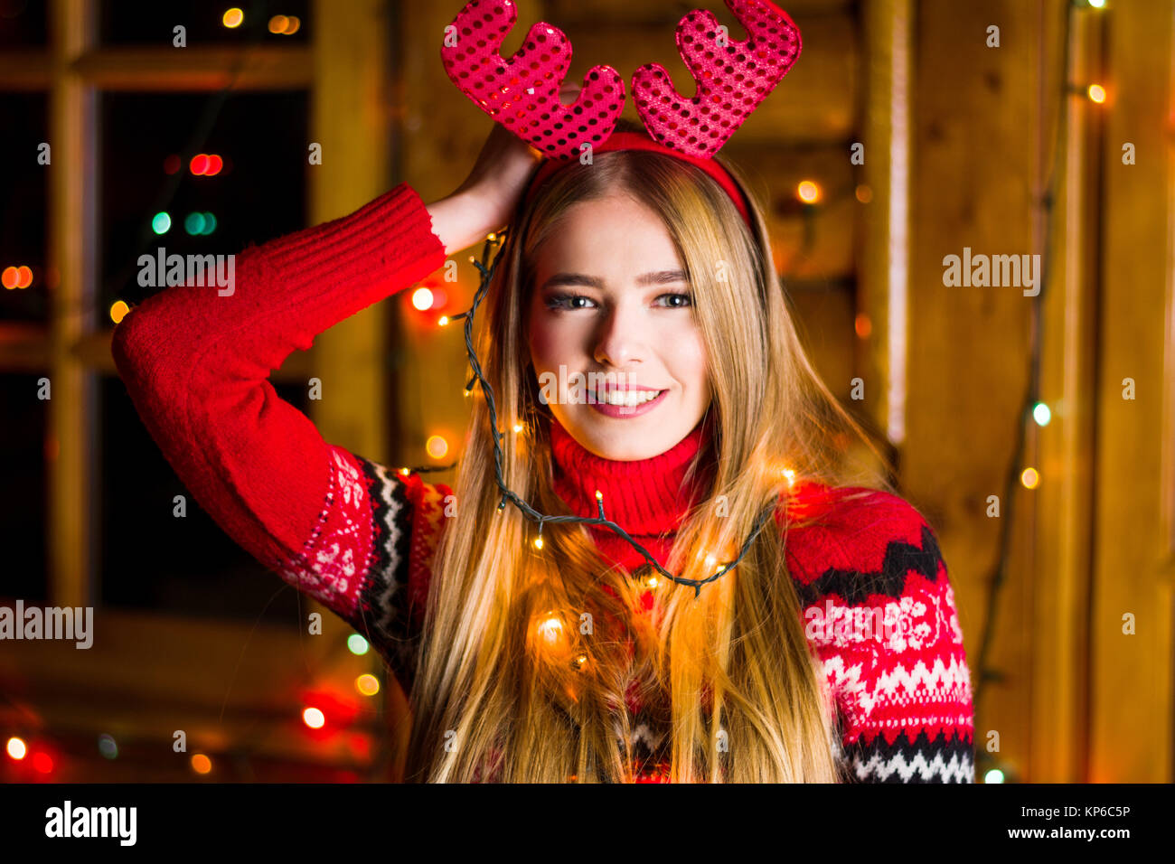 Schöne Mädchen mit festliche Lichter tragende rote Pullover in einem Haus anmelden Stockfoto