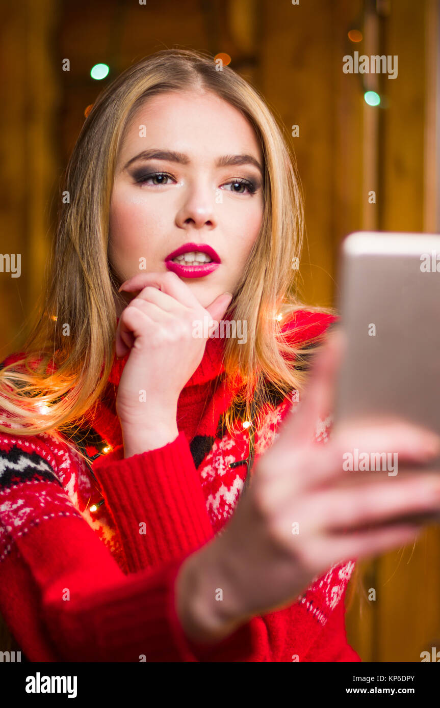 Mädchen nehmen einer selfie tragen eine festliche rot winter Pullover Stockfoto