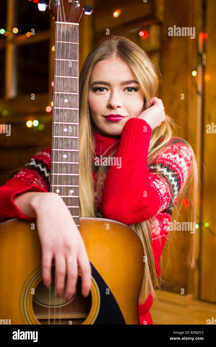 Schöne Mädchen mit akustischer Gitarre in festlicher Umgebung Stockfoto