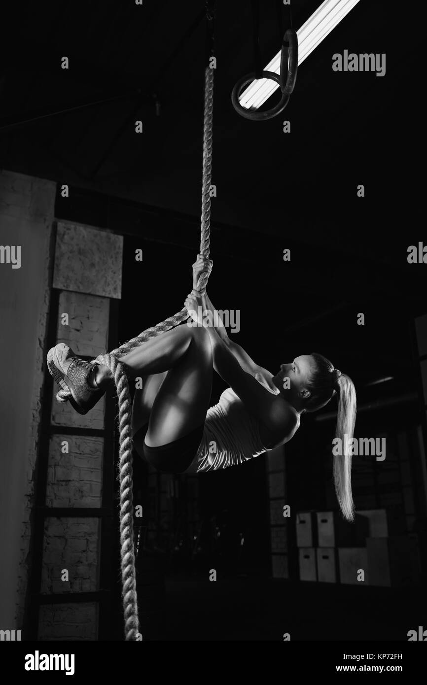 Vertikale Schuß einer Sportlerin Kletterseil im Fitnessstudio. Junge fitness weiblichen Athleten trainieren Sie im Fitnessraum mit Seil klettern Übung prepari Stockfoto
