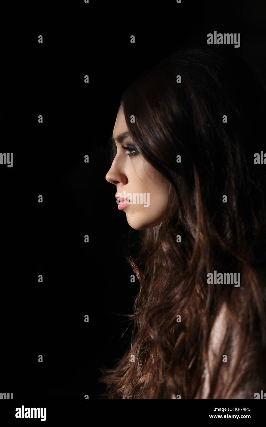 Portrait im Profil der Schönen traurigen Mädchen mit langen Locken gerade Suchen in der Dunkelheit Stockfoto
