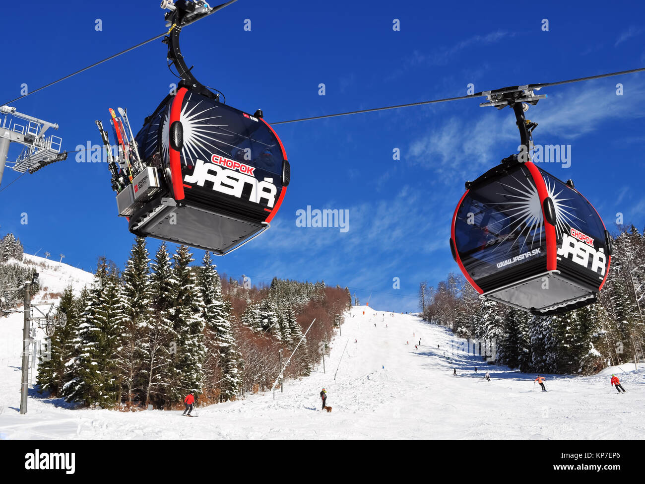 Jasna, Slowakei - Dezember 01, 2017: Zwei Kabinen der Luftseilbahn und Skifahrer am Hang des Berges Chopok Süd Seite an einem sonnigen Tag im Skigebiet re Stockfoto