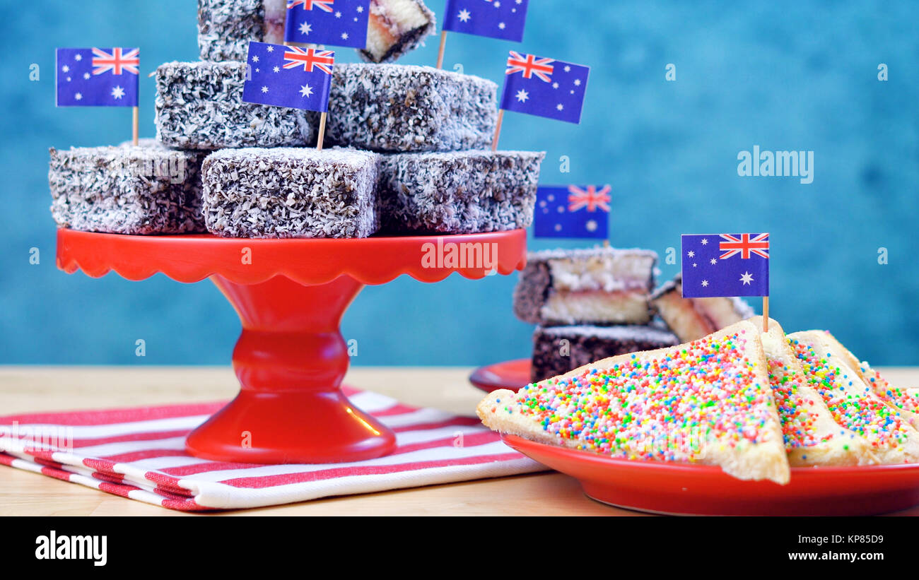 Iconic traditionelle australische Party Food, Lamington Kuchen und Märchen Brot, auf einem roten, weißen und blauen Hintergrund. Stockfoto