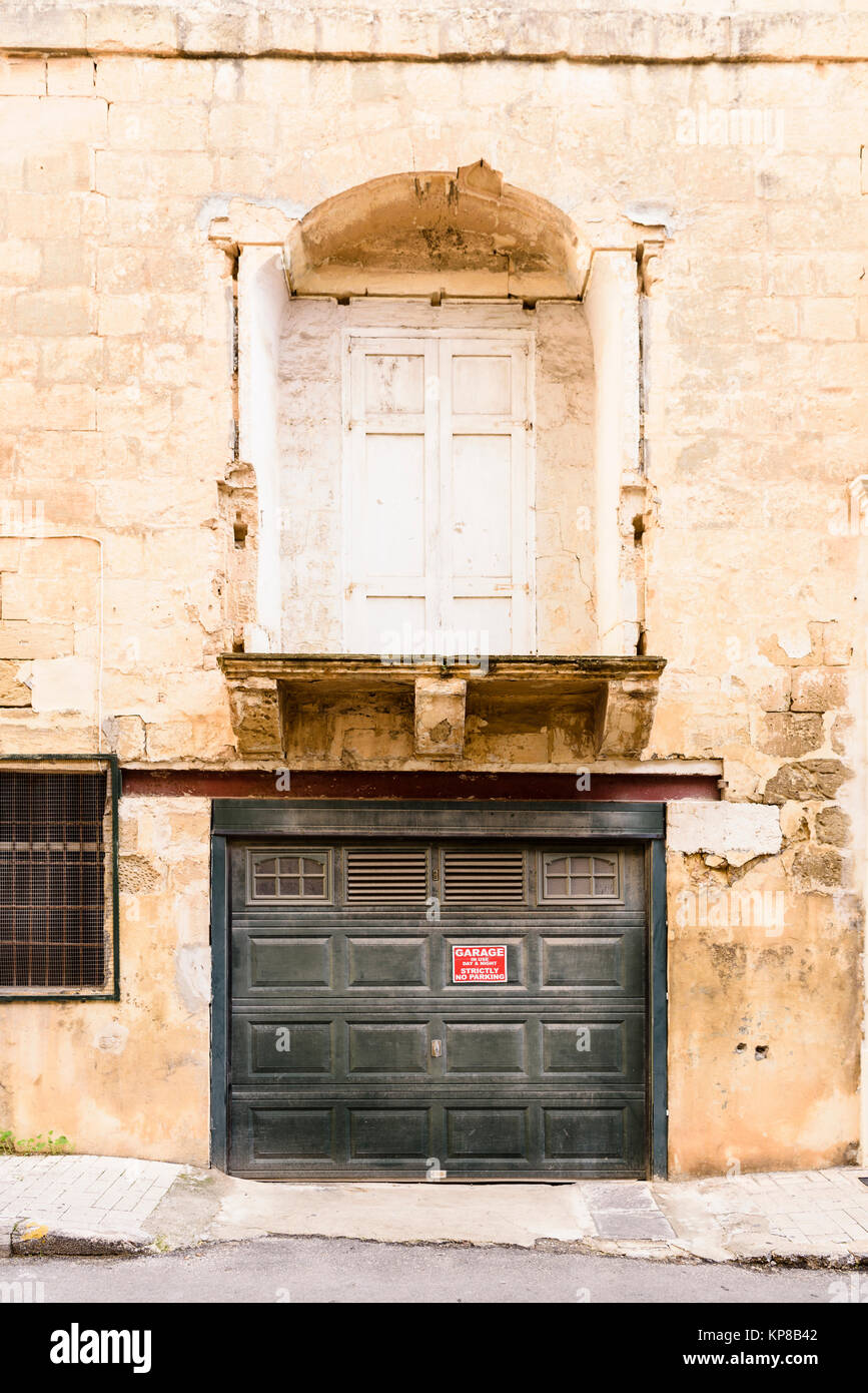 Traditionelles Haus auf Gozo, Malta aus dem frühen 20. Jahrhundert, mit einem der oberen Tür (fehlende Balkon) und ein bodennahes Garagentor. Stockfoto