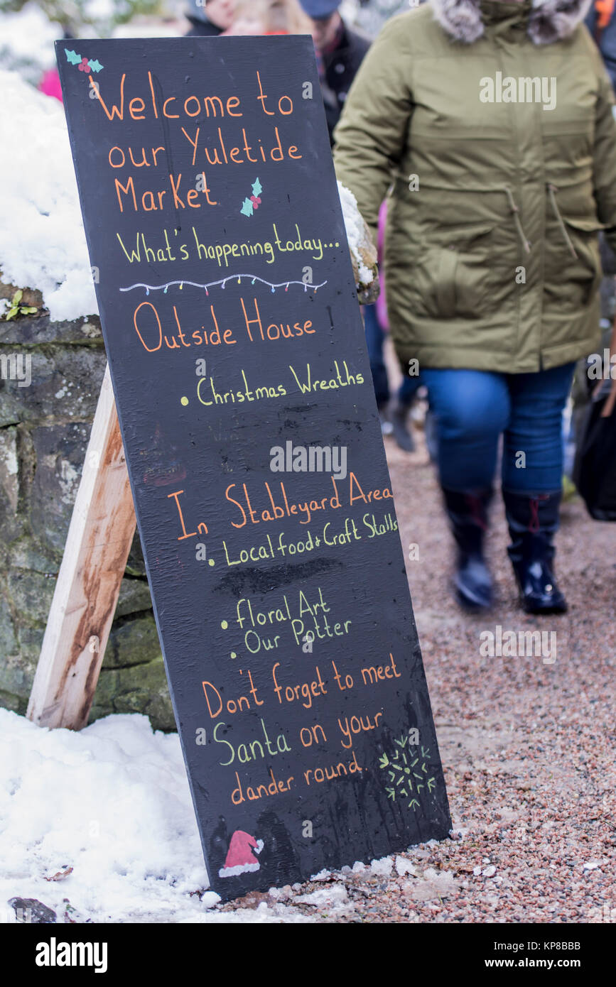 Besucher in eine Weihnachtliche außerhalb Markt im Schnee ein Board Beschreibung der Aktivitäten. Stockfoto