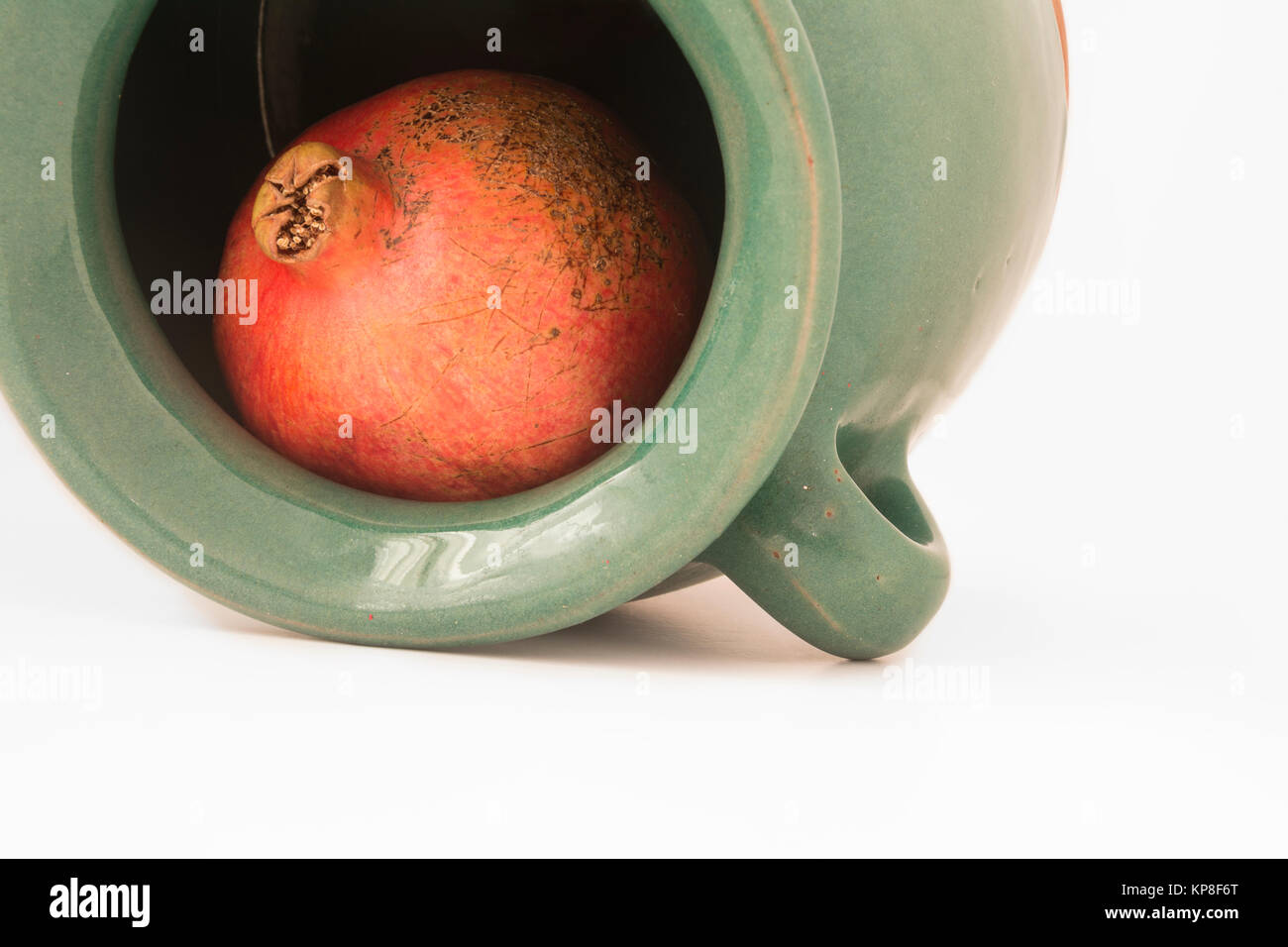 Nahaufnahme Blick auf ein roter Granatapfel im grünlich irdenes Gefäß Stockfoto