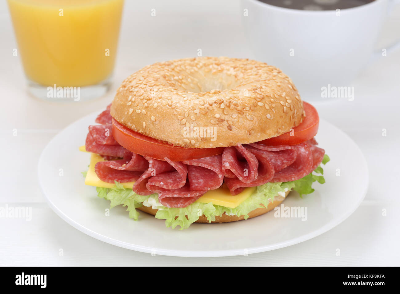 Bagel Brötchen für das Frühstück mit Salami, Schinken, Kaffee und Orangensaft Stockfoto