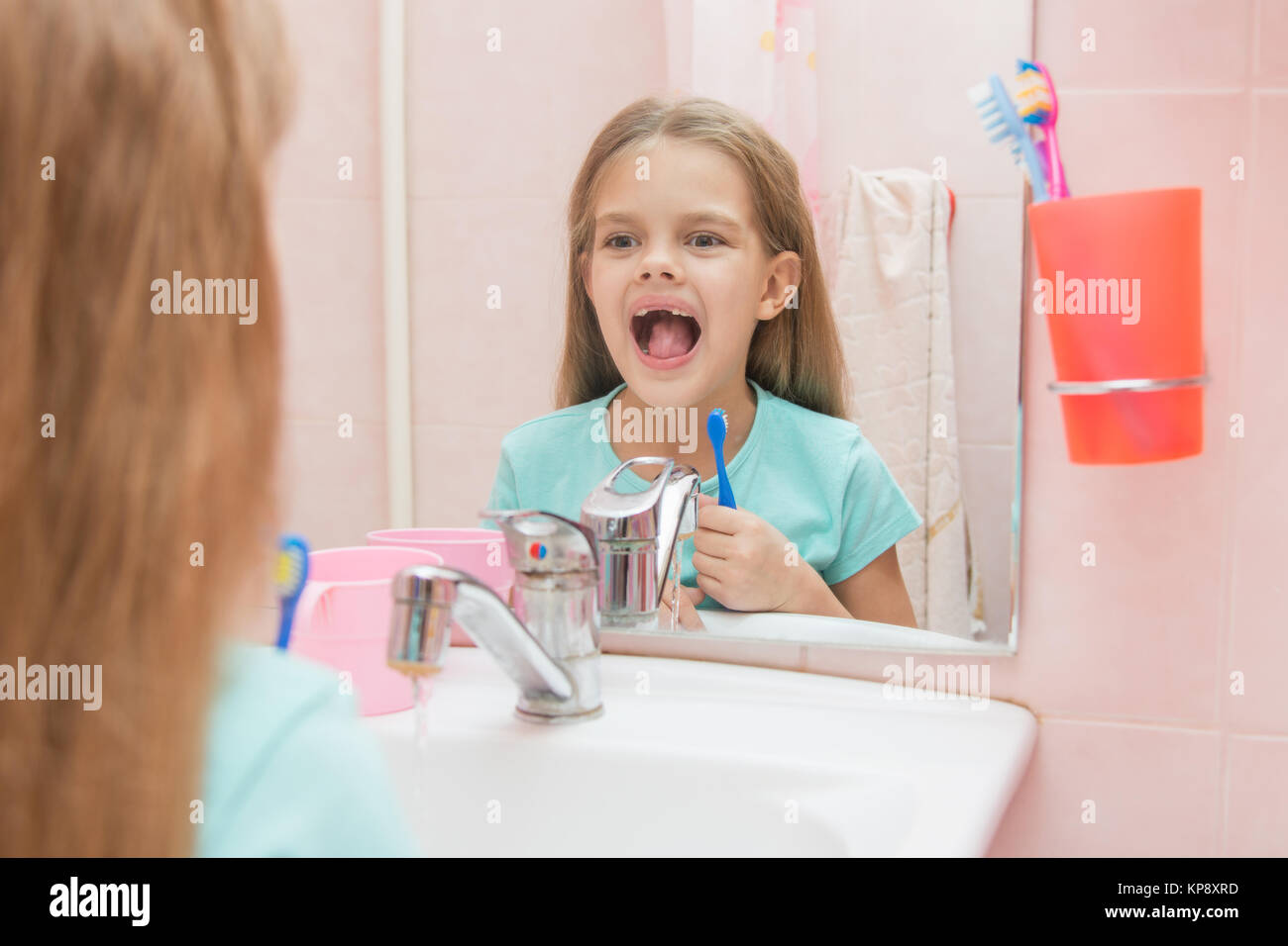 Sechs Jahre altes Mädchen ihren Mund öffnen behandelt Zähne in der Reflexion in einem Spiegel, während im Bad Stockfoto