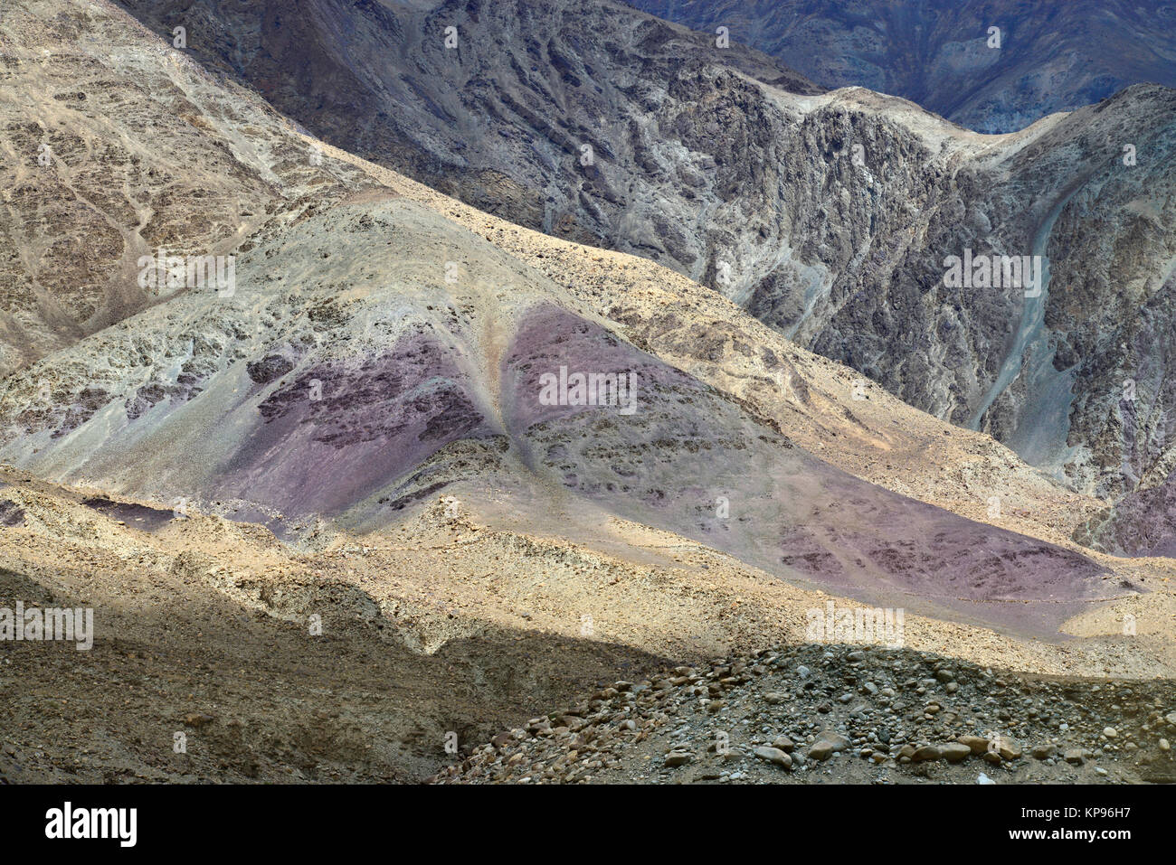 Berghänge von hellen Farben: violett Felsen im Vordergrund, Hintergrund Grauer Rock. Stockfoto