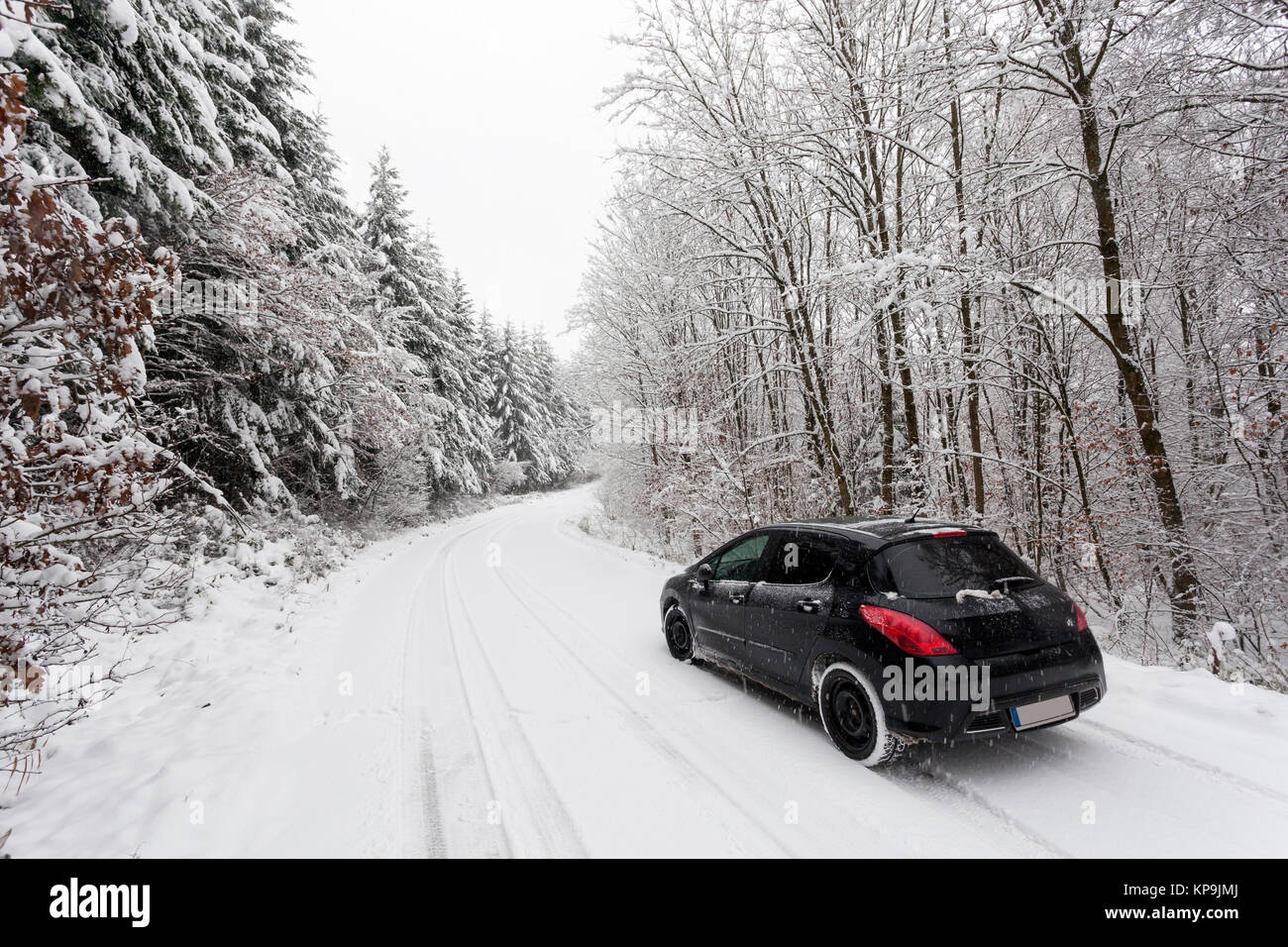 Auto auf einer verschneiten Straße in einem Snowy White Winter Forest in Deutschland Stockfoto