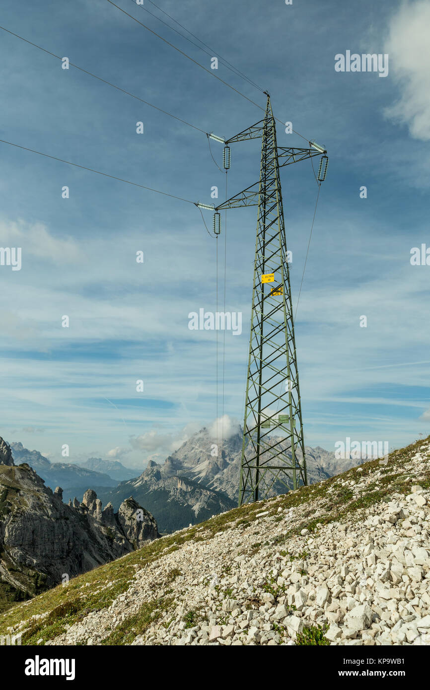 Strommasten und Leitungen in der Berglandschaft der Dolomiten, Strom auf einem ländlichen Bergregion in sonniger Tag. Stockfoto