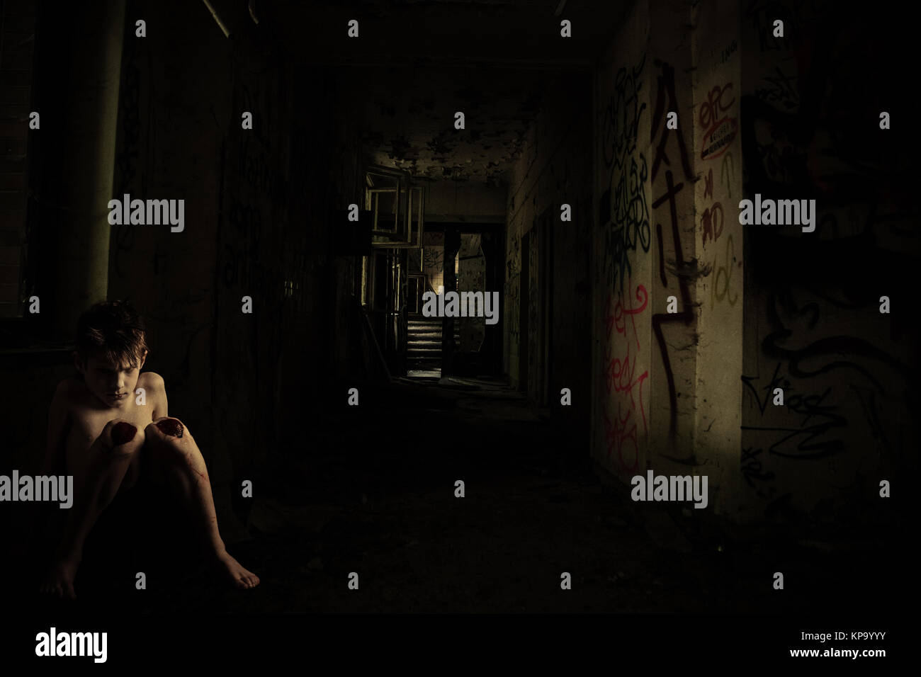 Verletzte Junge sitzt in einem verlassenen Haus Stockfoto