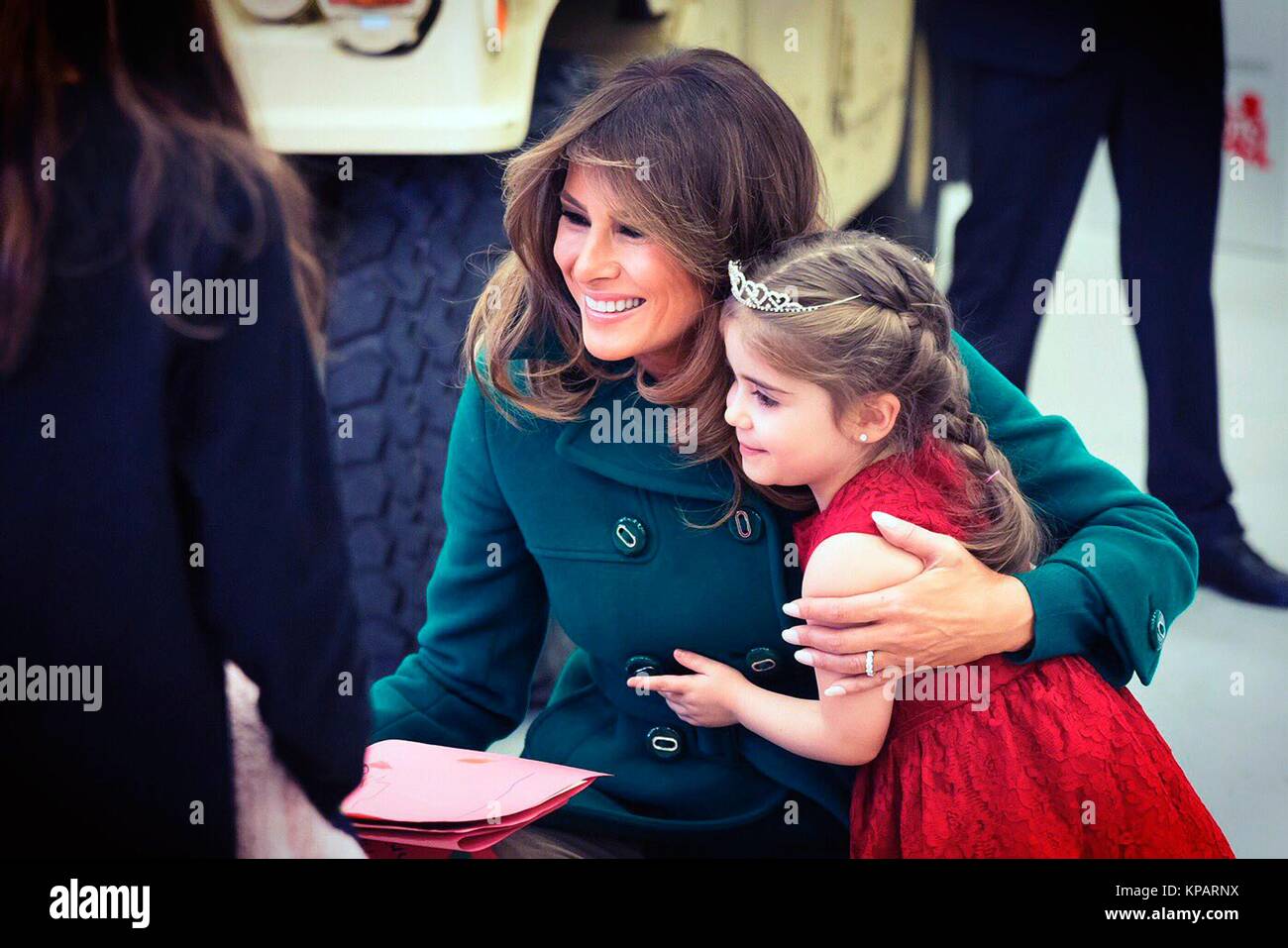 Washington, Vereinigte Staaten von Amerika. 14 Dez, 2017. First Lady der USA Melania Trump Umarmungen ein junges Mädchen während der jährlichen Marine Corps Stiftung Spielwaren für Tots bei Joint Base Anacostia-Bolling Dezember 13, 2017 in Washington, DC. Die erste Dame folgte die langjährige Tradition der anderen Tannen Damen in helfenden Kindern Karten, sortiert Spielzeug, und der Nächstenliebe, die Veranstaltung zu Ehren. Credit: Planetpix/Alamy leben Nachrichten Stockfoto