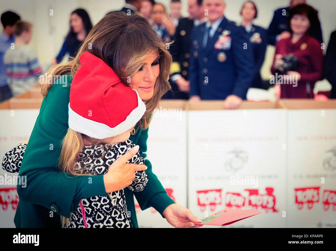 Washington, Vereinigte Staaten von Amerika. 14 Dez, 2017. First Lady der USA Melania Trump Umarmungen ein junges Mädchen während der jährlichen Marine Corps Stiftung Spielwaren für Tots bei Joint Base Anacostia-Bolling Dezember 13, 2017 in Washington, DC. Die erste Dame folgte die langjährige Tradition der anderen Tannen Damen in helfenden Kindern Karten, sortiert Spielzeug, und der Nächstenliebe, die Veranstaltung zu Ehren. Credit: Planetpix/Alamy leben Nachrichten Stockfoto