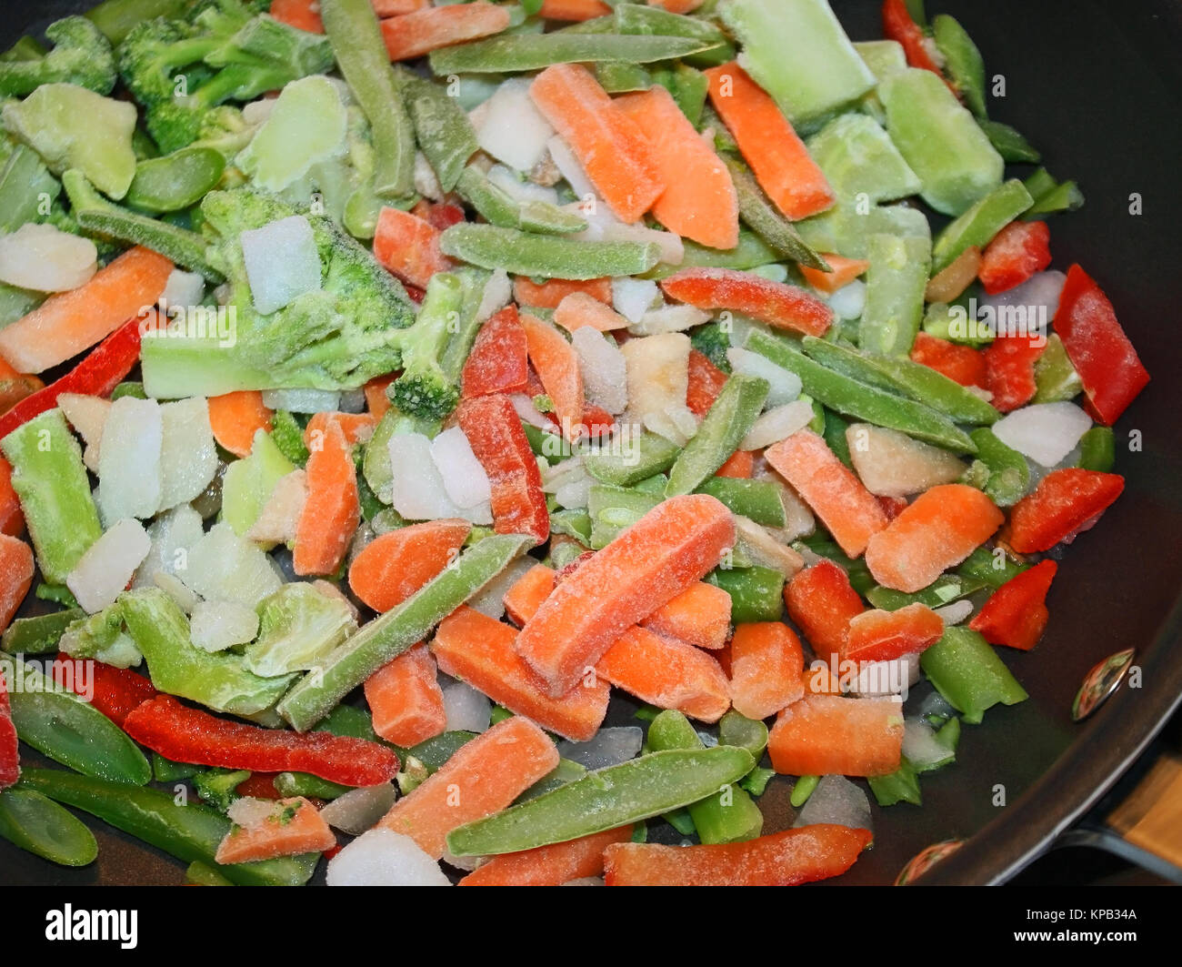 Ein Sortiment von rohem Gemüse in einem antihaftbeschichtete Pfanne zum Kochen bereit. Gefrorene Möhren, Paprika, Bohnen, Zwiebeln, Broccoli Stockfoto