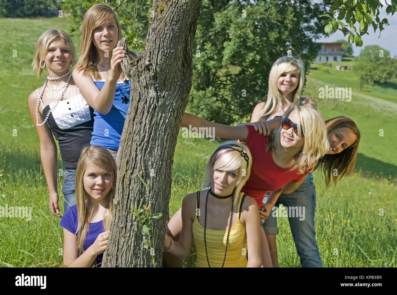 Model Release, Jugendliche Maedchen Stehen um Einen Baumstamm in der Wiese - Mädchen im Teenageralter Stockfoto
