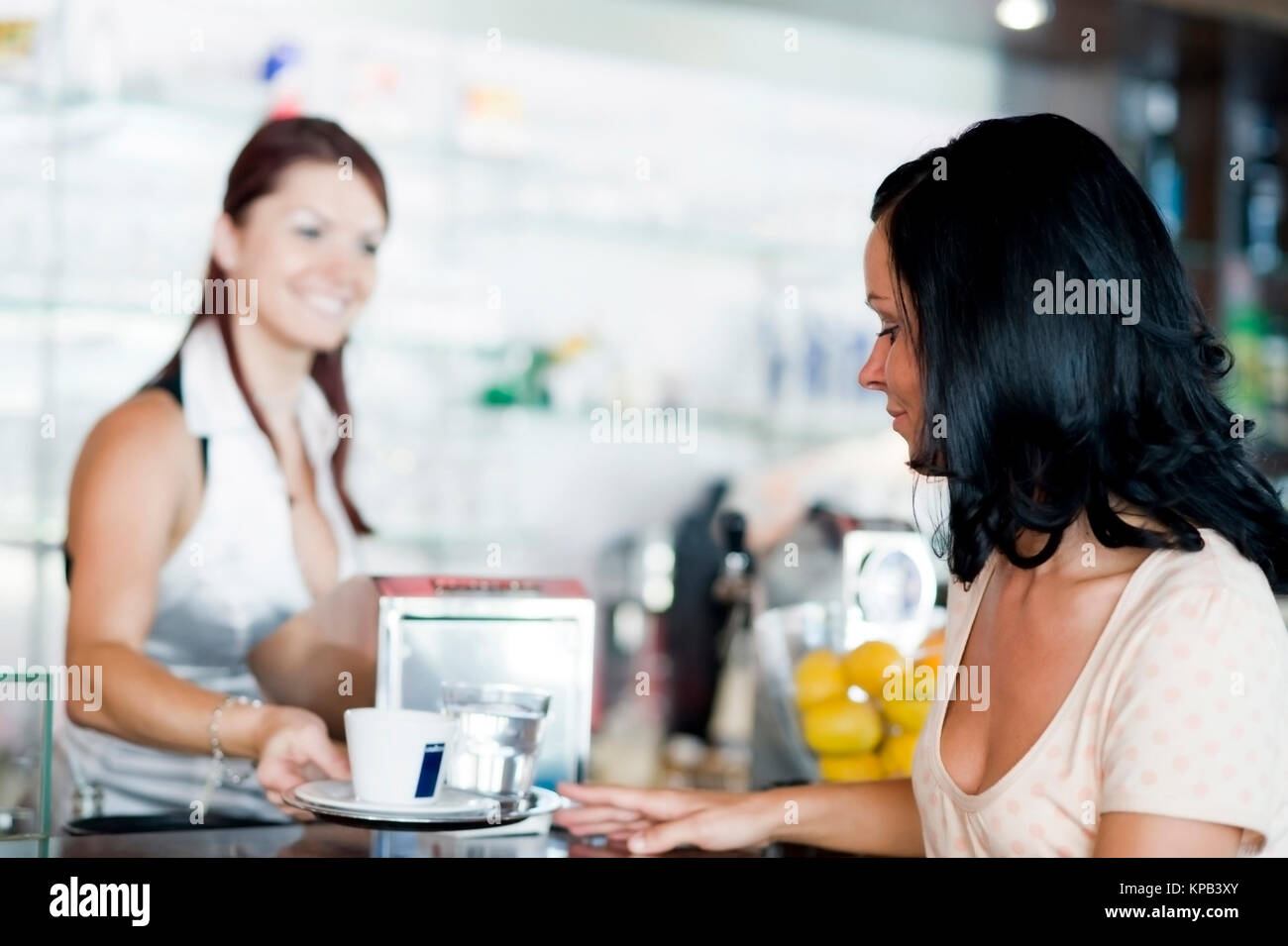 Model Release, Kellnerin Bedient Junge Frau Im Kaffeehaus ein der Theke - junge Frau in cafeteria Stockfoto