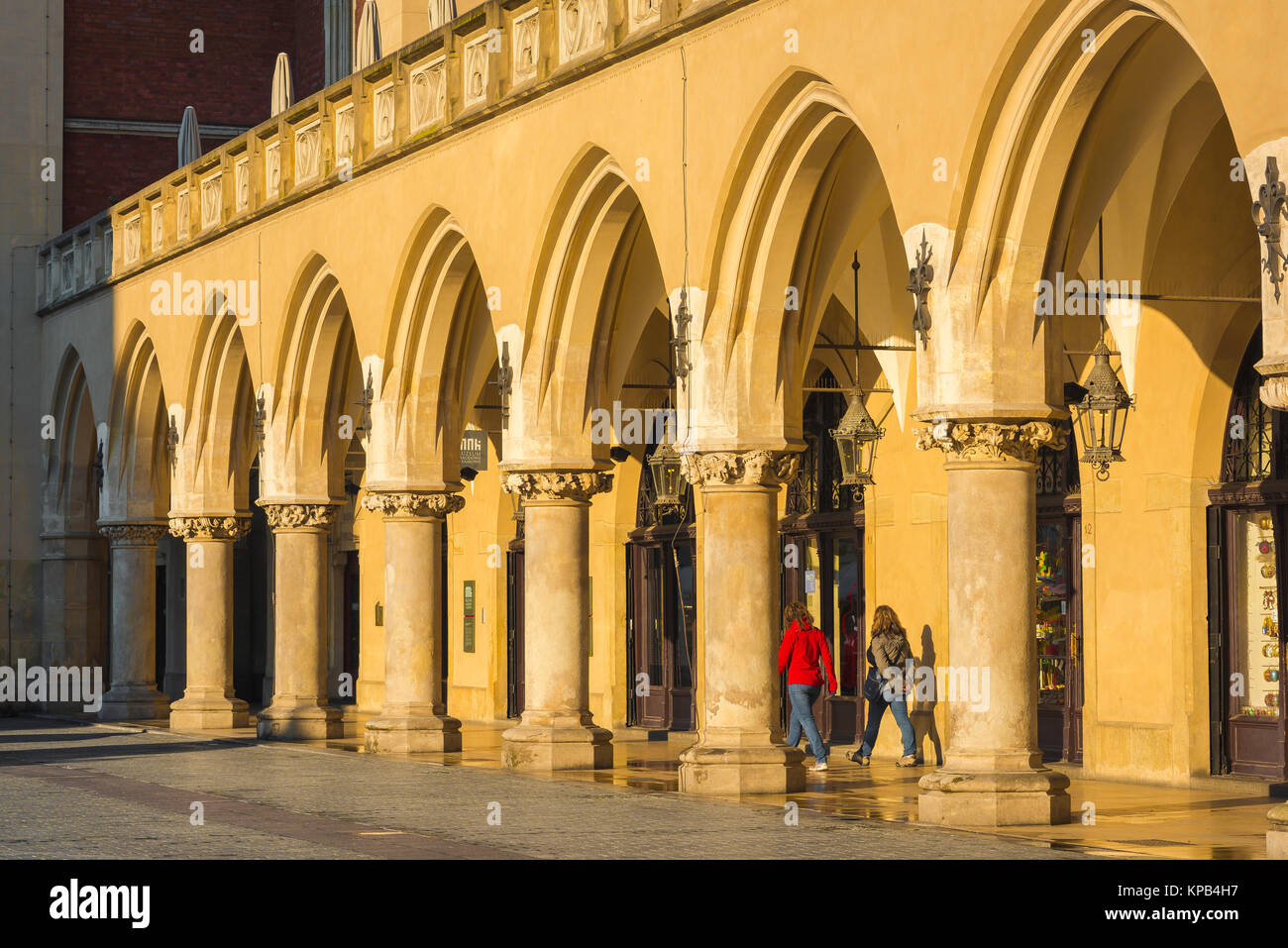 Kolonnade arcade Europa, zwei junge Frauen durch einen Säulengang der Renaissance Tuchhallen (Sukiennice) auf dem Marktplatz in Krakau, Polen. Stockfoto