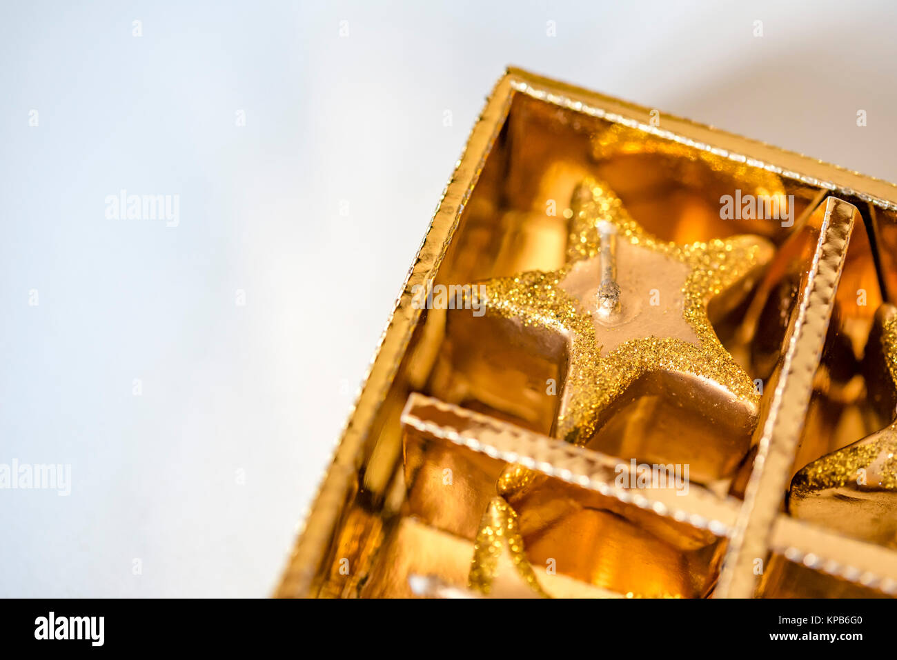 Golden glitzernden Weihnachtsschmuck in Feld auf Weiß, Zimmer für Kopieren. Nahaufnahme des festlichen sternförmigen Kerzen in Gold, Raum für Text. Stockfoto