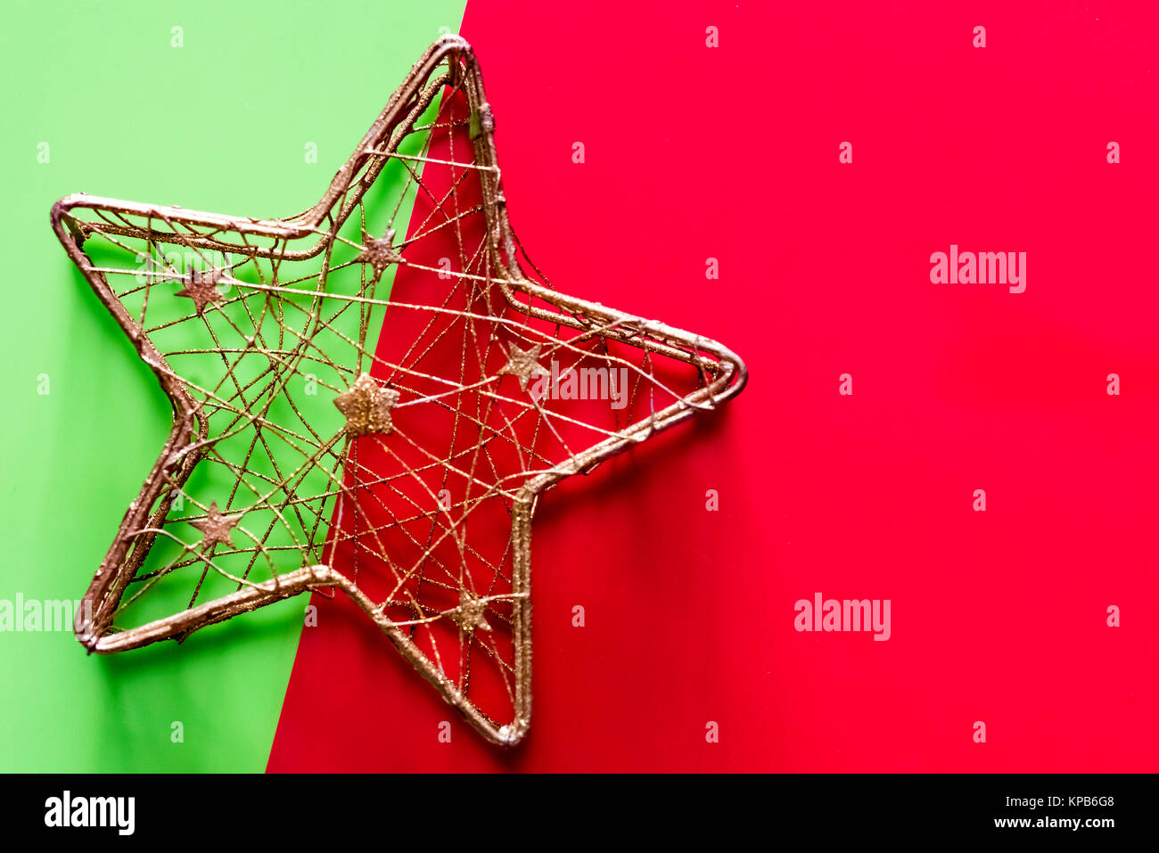 Moderne Gold Star Weihnachten Dekoration auf Grün und Rot, Raum für Text. Golden festliche Ornament, Ansicht von oben, Raum für Kopieren. Stockfoto