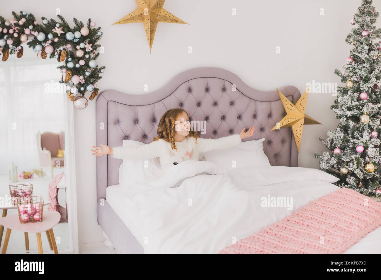 Portrait von niedlichen Lustige kleine Mädchen am Weihnachtsmorgen in Weiß Home Interior. Kind fröhlich im Bett sitzen. Horizontale Farbbild. Stockfoto