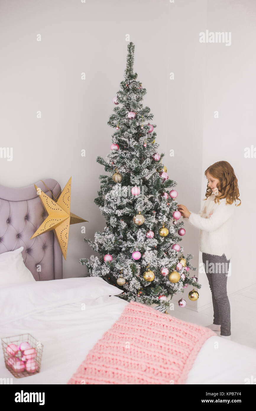 Portrait von niedlichen glückliche kleine Mädchen ihre Familie helfen Weihnachtsbaum im Wohnzimmer zu verzieren. Kind hängend Urlaub Dekorationen. Vertikale Farbe pho Stockfoto