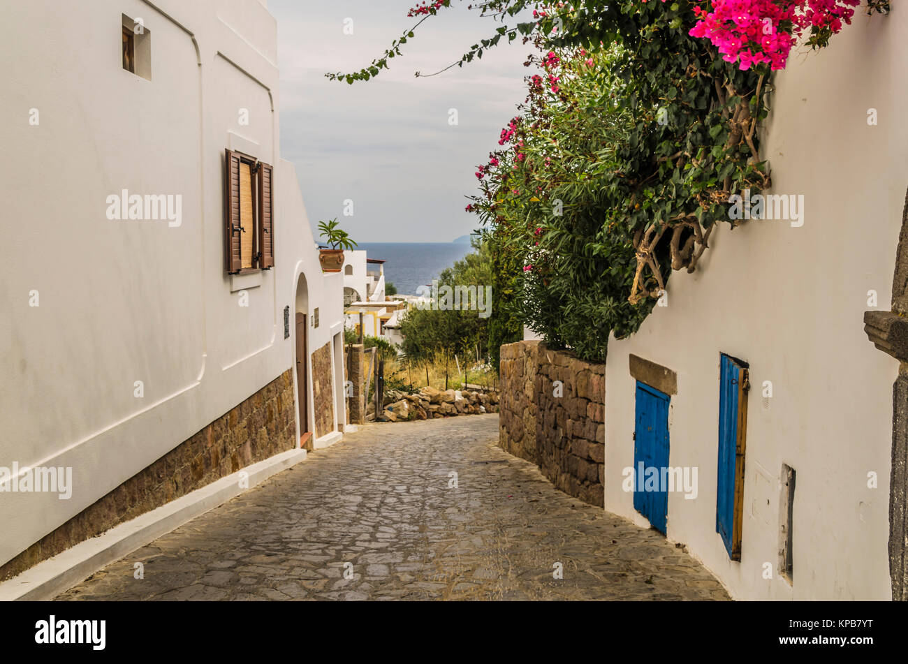 Straße der Steine und weiße Häuser mit bunten Blumen und das Meer tyrrhenischen Hintergrund panarea Eine der Äolischen Inseln Stockfoto