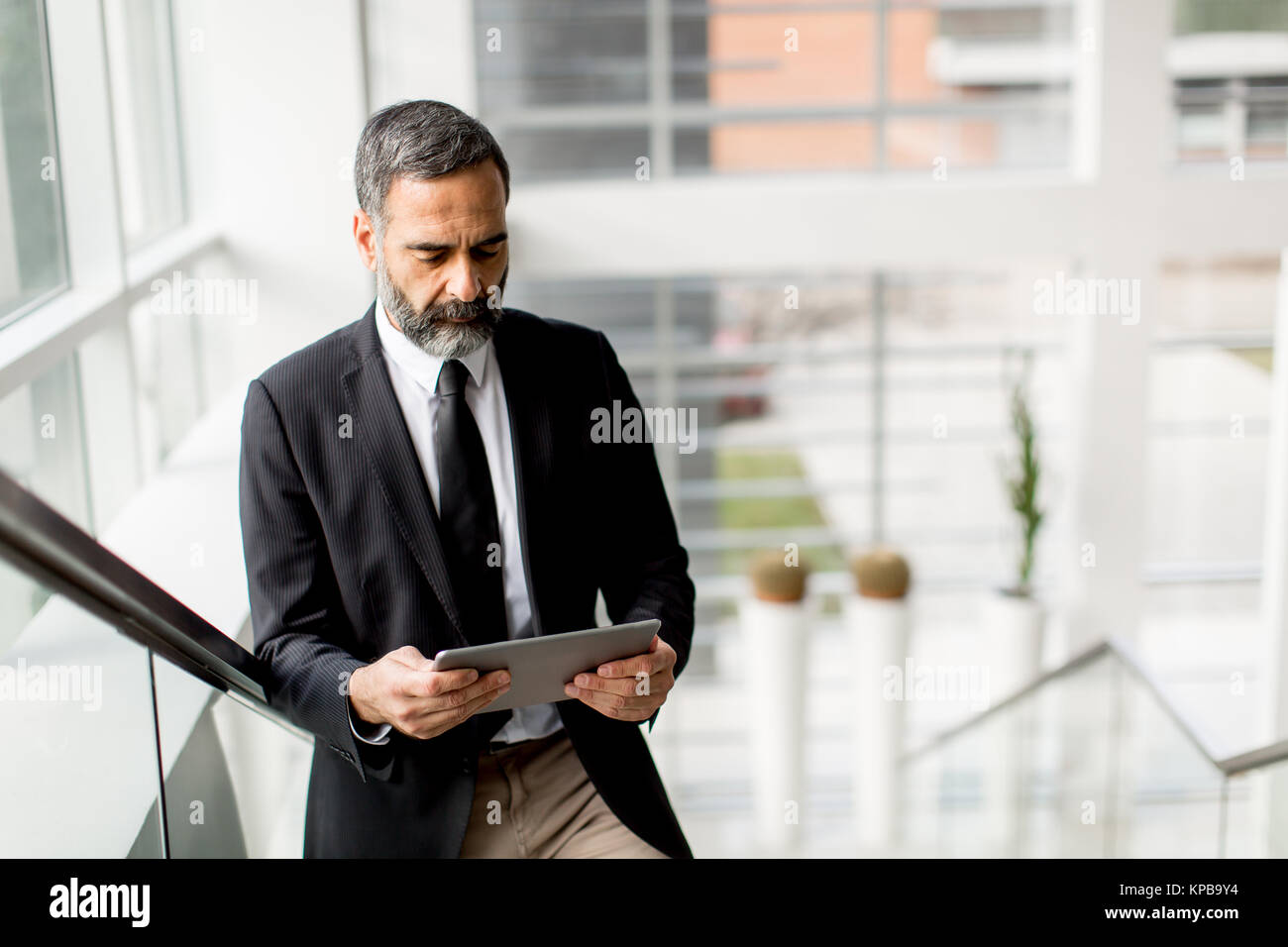 Stattliche mittleren Alter Geschäftsmann mit digitalen Tablet in der modren Büro Stockfoto