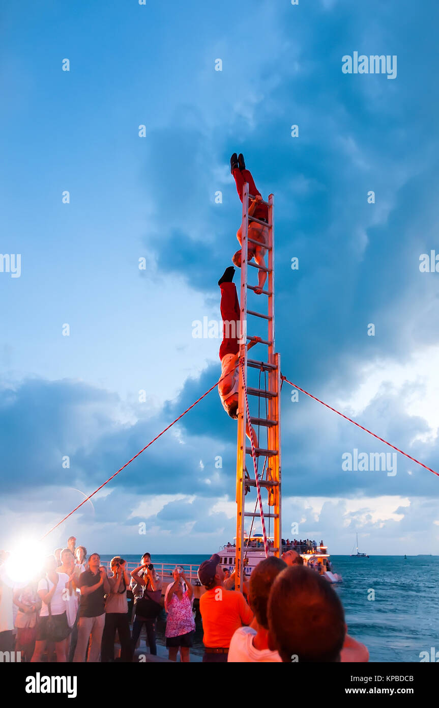 Akrobaten auf Leiter durchführen, vertikaler Ständer bei Sonnenuntergang Feier Key West Florida Stockfoto